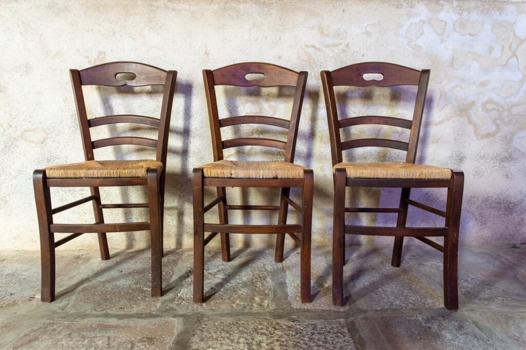 Three wooden chairs with woven seats in a rustic interior setting.