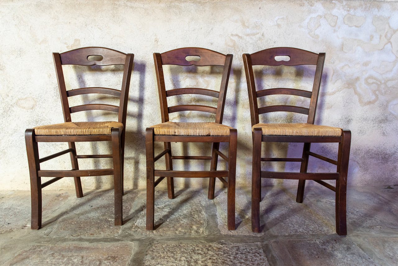 Three wooden chairs with woven seats in a rustic interior setting.
