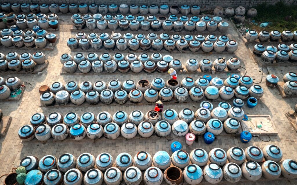 Rows of fish sauce jars in a Vietnamese courtyard, showcasing traditional fermentation and local culture.